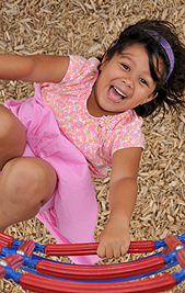child holding onto playground equipment